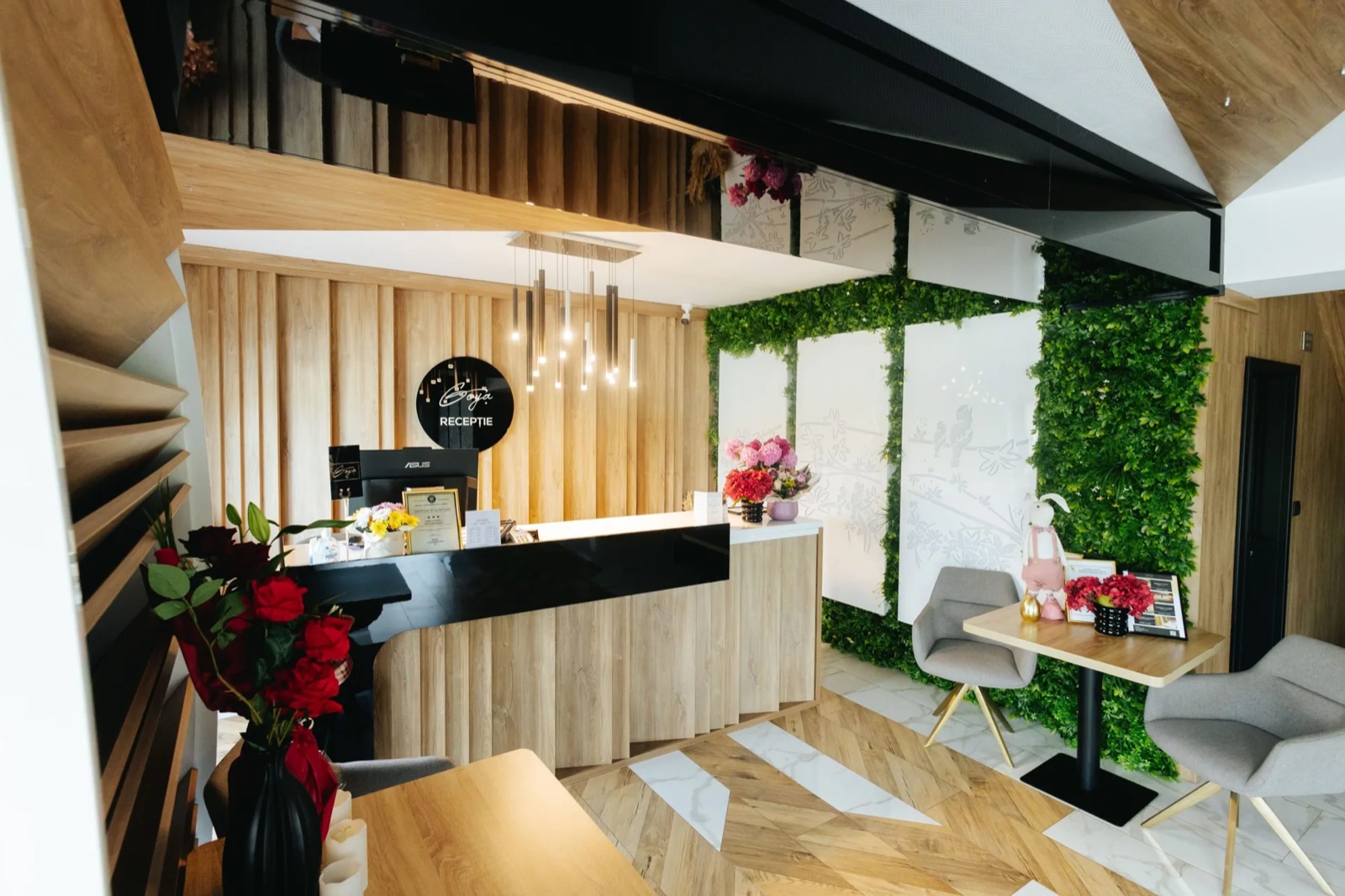 Recepția Hotel Goya Boutique din Târgu Jiu, cu lemn deschis, plante și sigla Goya Recepție.