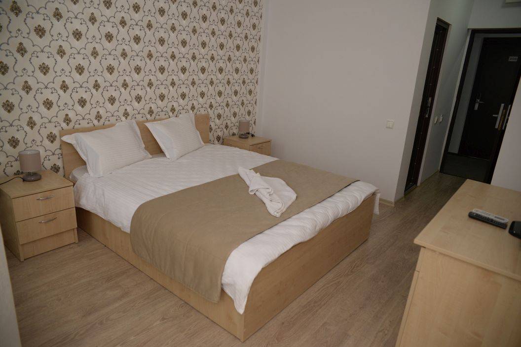 Cameră dublă la Hotel Story Târgu Jiu, cu mobilier din lemn și tapet decorativ.