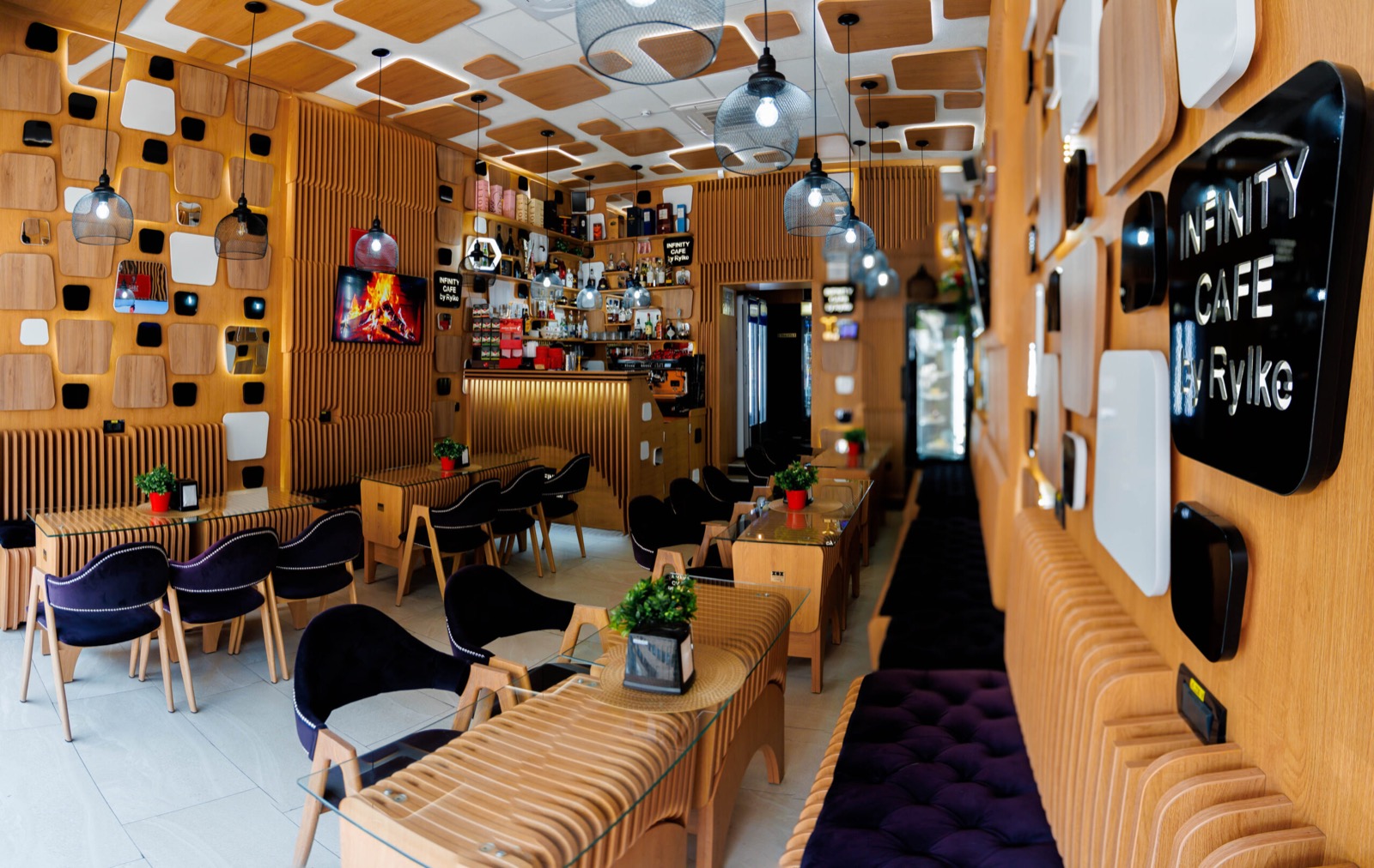 Interiorul Infinity Café by Rylke din Târgu Jiu, cu mese, bar și marca localului.